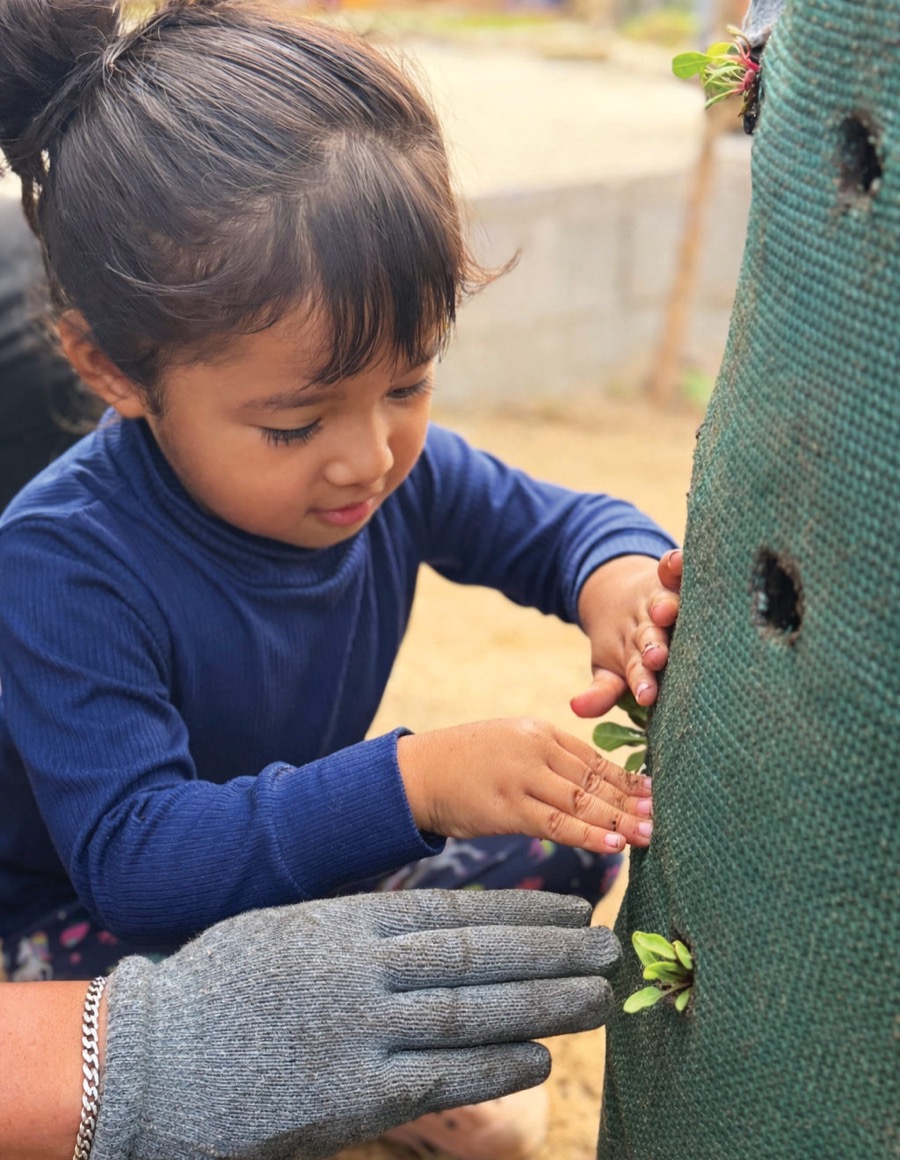 A young girl plants a seedling in a Garden Tower