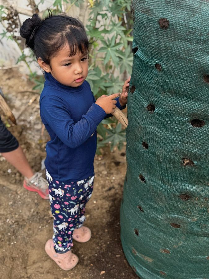 A young girl reaches into a tall Garden Tower