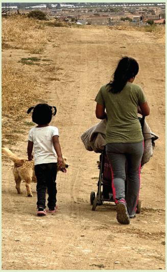 A mother and child walk down a dirt road