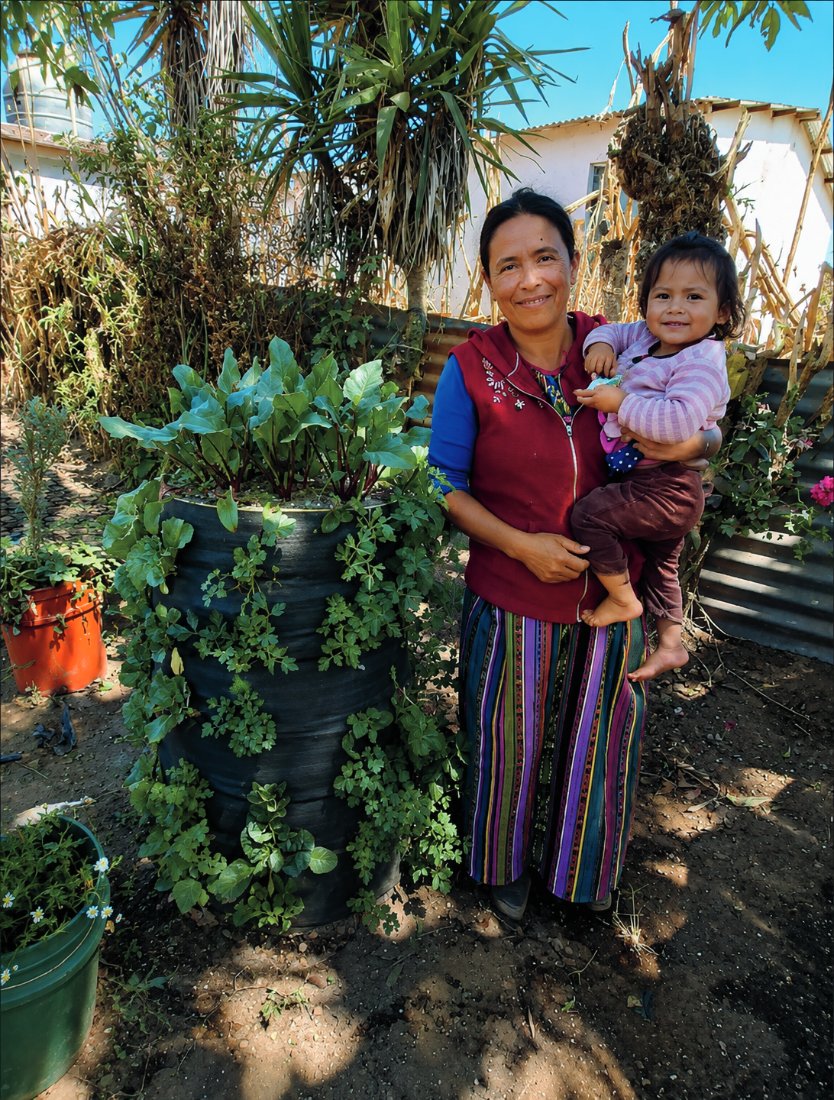 Mirna Morales holding her daughter beside their Garden Tower in Guatemala