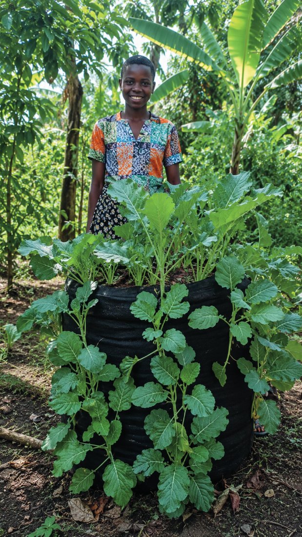 Baseme Muzerero standing behind her Garden Tower in Uganda