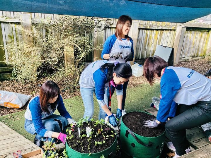 Volunteers plant vegetables in a Garden Tower