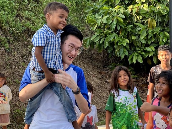 A volunteer carries a smiling child on his shoulders